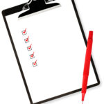 Checklist on clipboard, with red pen.