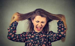 Very angry upset woman pulling her hair out screaming