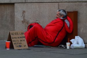 homeless man in sleeping bag begging