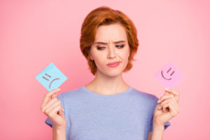 Woman looking at happy or sad post it notes