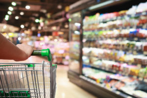 woman hand hold supermarket shopping cart with Abstract grocery store