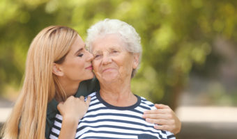 Woman with elderly mother outdoors on sunny day